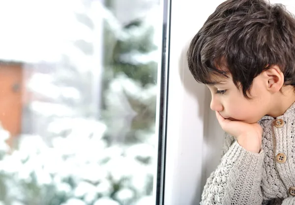 A criança triste na janela não pode sair por causa de frio e neve — Fotografia de Stock