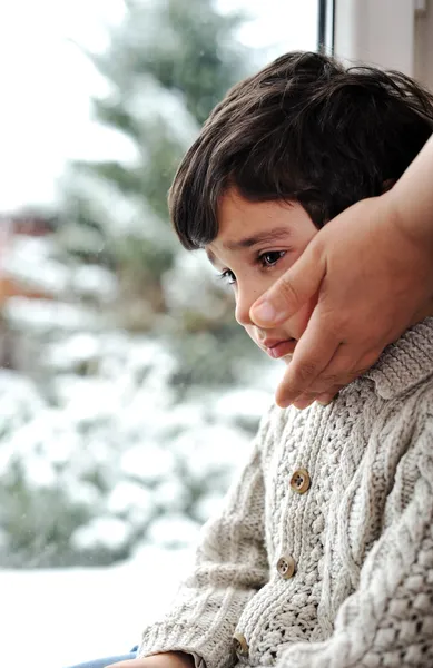 Niño triste en la ventana y la nieve de invierno está fuera — Foto de Stock