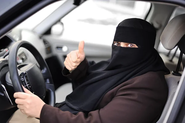 Árabe musulmana mujer conducir un coche con el pulgar hacia arriba —  Fotos de Stock