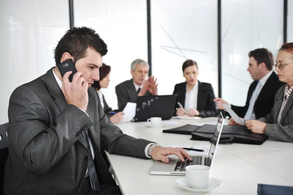 Uomo d'affari che parla al telefono e digita sul computer portatile durante una riunione — Foto Stock