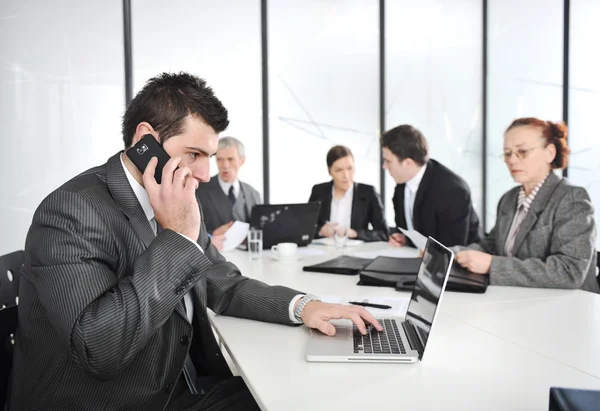 Бизнесмен звонит по телефону, деловая встреча на заднем плане — стоковое фото
