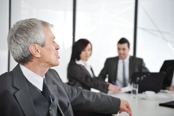 Senior businessman at a meeting. Group of colleagues in the background — Stock Photo, Image