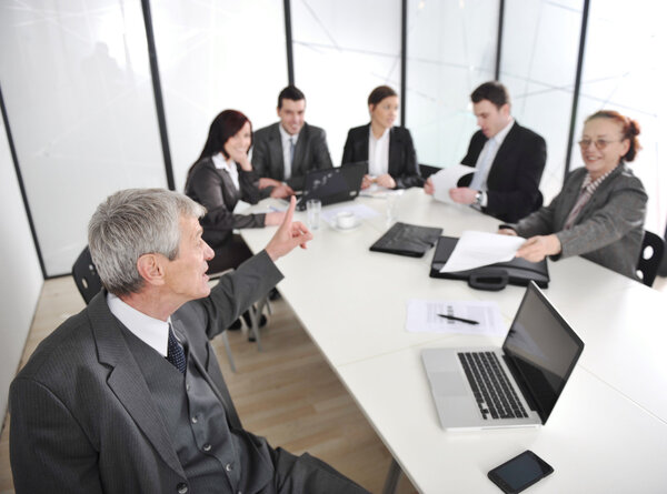 Senior businessman at a meeting. Group of colleagues in the background