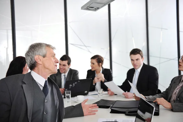 Senior businessman at a meeting. Group of colleagues in the background — Stock Photo, Image