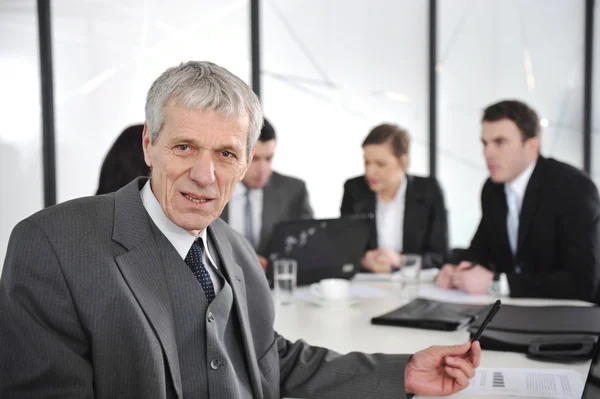 Leitender Geschäftsmann bei einem Treffen. Gruppe von Kollegen im Hintergrund — Stockfoto