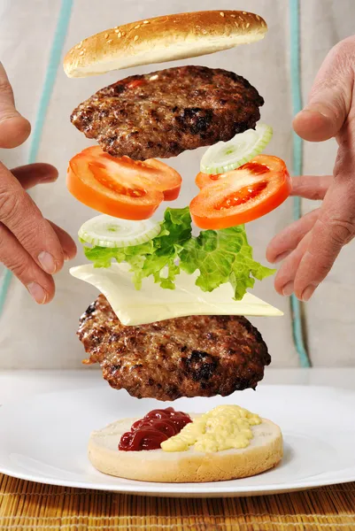 Levitating zero gravity burger in hands — Stock Photo, Image