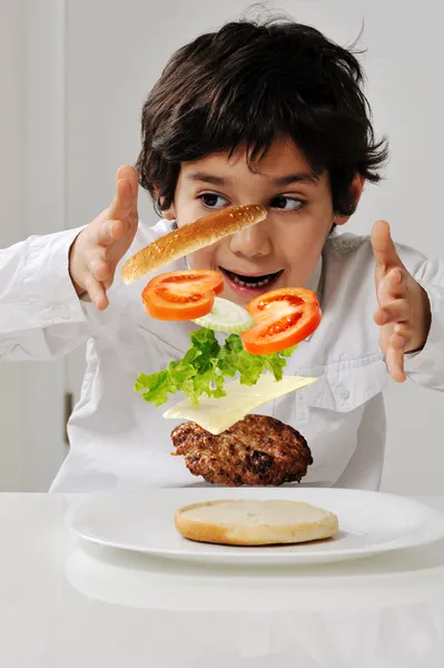 Liten pojke med hamburger ingredienser i händer — Stockfoto