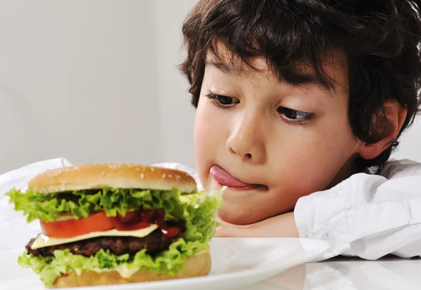 Menino em tentação com hambúrguer — Fotografia de Stock