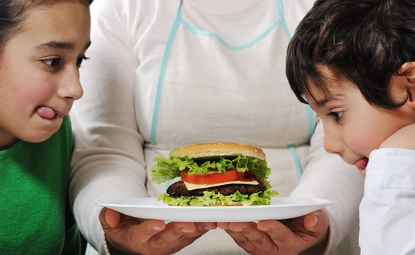 ママ男の子と女の子のためのおいしいハンバーガーを準備 — ストック写真