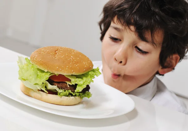 Малюк на спокусі зі смачним гамбургером — стокове фото