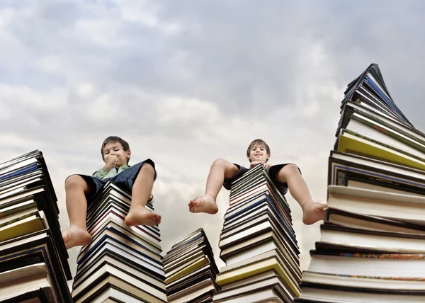 Kisfiú, nagy halom könyvet ül — Stock Fotó