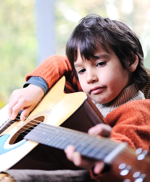Niño tocando la guitarra en casa Imagen de archivo