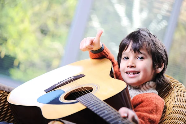 Liten pojke spelar gitarr hemma Stockbild