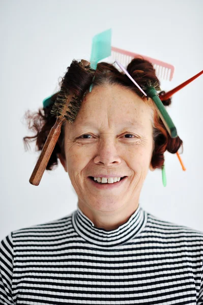 Senior female multitasking with many combs in hair Stock Picture