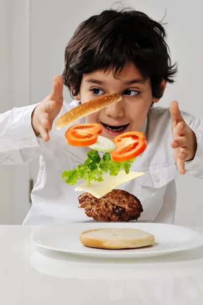 Little boy with hamburger ingredients in hands — Stock Photo, Image