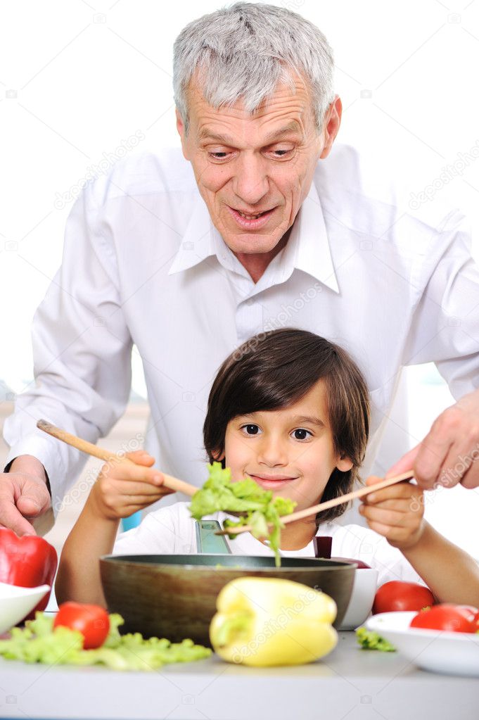 Grandfather and little boy in kitchen cooking together