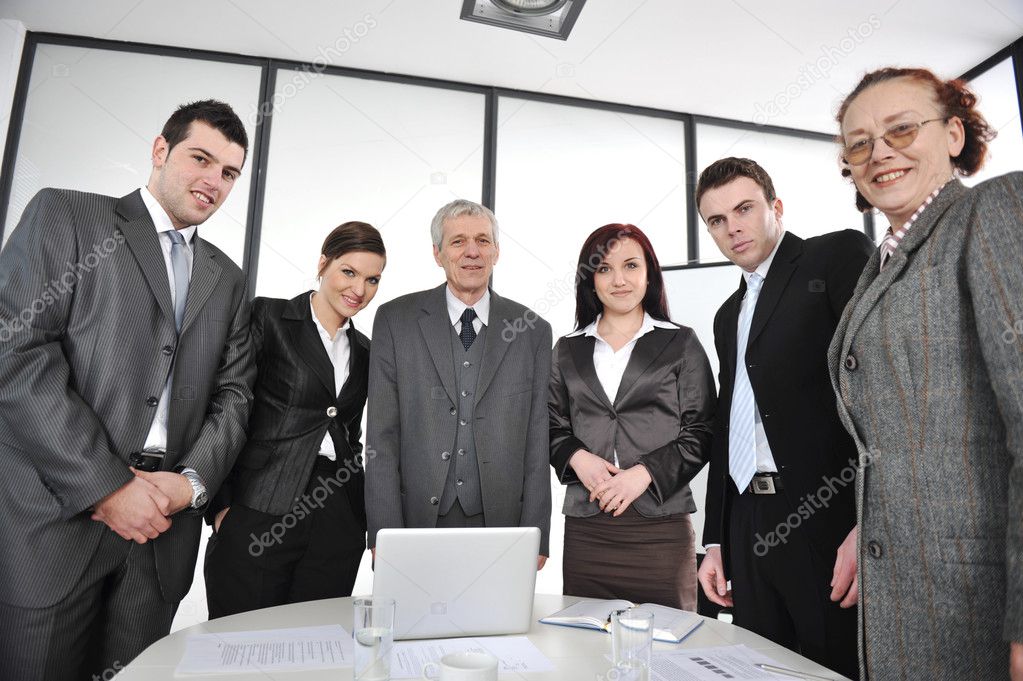 Multi aged business standing around the table at office