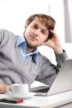 Relaxed young man in office clipart