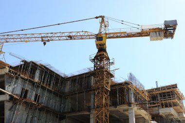 Buildings under construction and cranes under a blue sky clipart