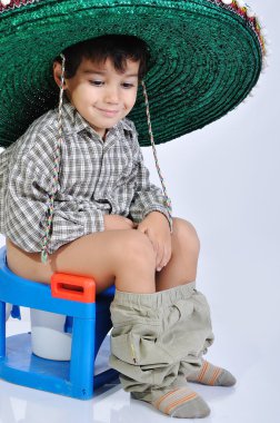 Cute kid with mexican hat on head, sitting on toilet clipart