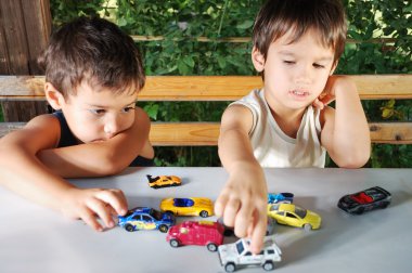 Children playing with cars toys outdoor in summer time clipart