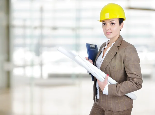 stock image Female architect holding blueprints with helmet on head