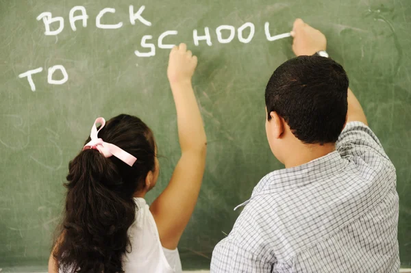 Tillbaka till skolan - pojke och flicka skriver ombord i klassrummet — Stockfoto
