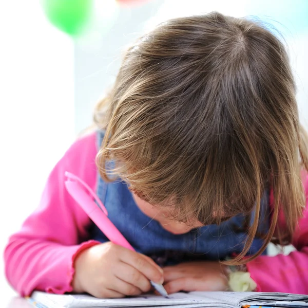 Pequeña linda niña rubia está dibujando con lápiz sobre papel — Foto de Stock