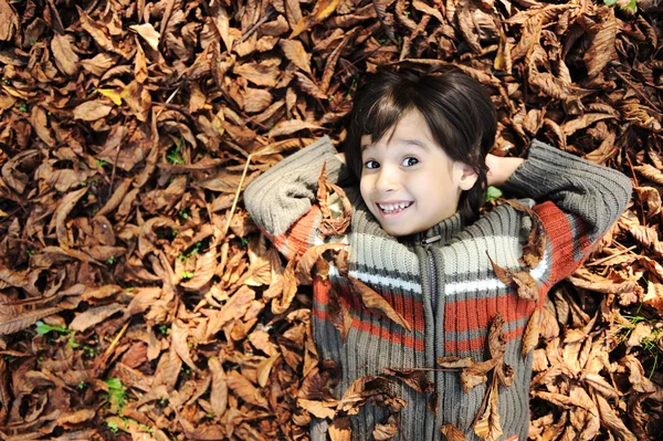 Un bambino che gioca nelle foglie autunnali — Foto Stock