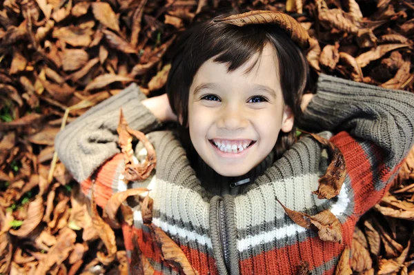 Uma criança brincando nas folhas de outono — Fotografia de Stock