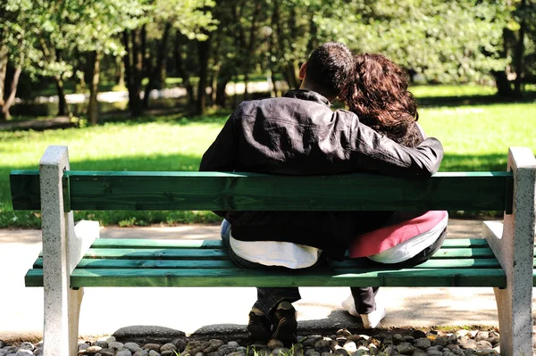 爱的年轻情侣在公园的长凳上 — 图库照片