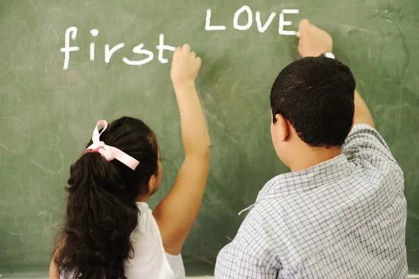 Premier amour - garçon et fille écrivant à bord en classe — Photo