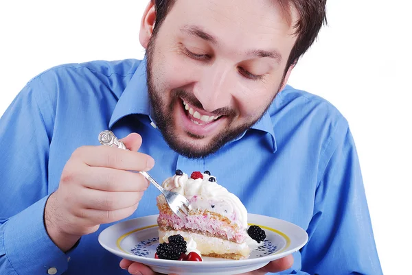 Молодой человек ест красочный торт, изолированный — стоковое фото