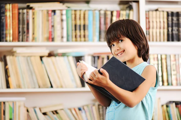 Kid med bok i biblioteket — Stockfoto