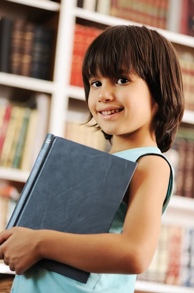 Kid with book in library — Stock Photo, Image