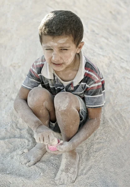 Πορτρέτο της φτώχειας, μικρό κακή βρώμικα αγόρι που παίζει στην άμμο — Φωτογραφία Αρχείου