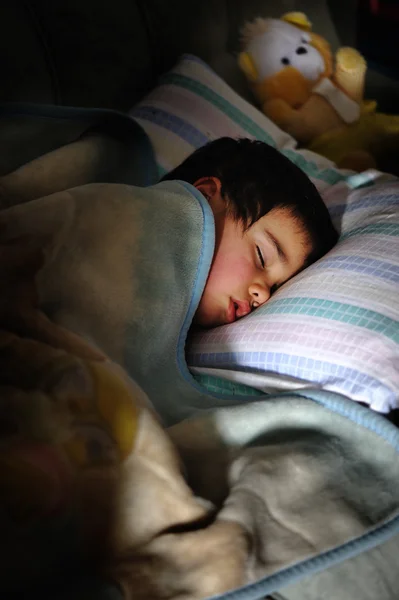 Bambino che dorme in camera oscura con orsacchiotto — Foto Stock