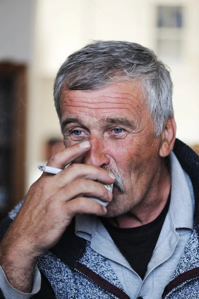 Старик с усами курит сигарету и пьет кофе. — стоковое фото