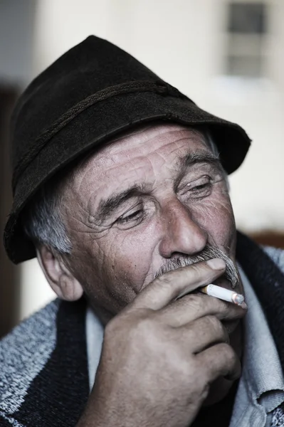 Nahaufnahme künstlerisches Foto eines alten Mannes mit grauem Schnurrbart, der Zigarette raucht — Stockfoto