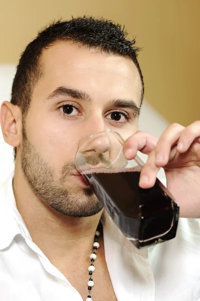 Young attractive man drinking cherry juice — Stock Photo, Image