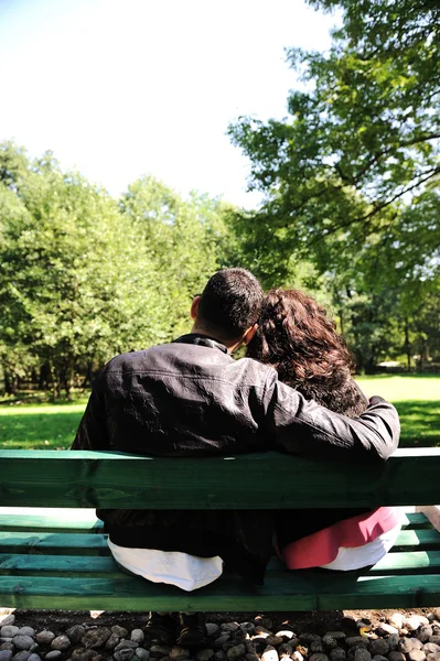 Mladí milující pár na lavičce v parku — Stock fotografie
