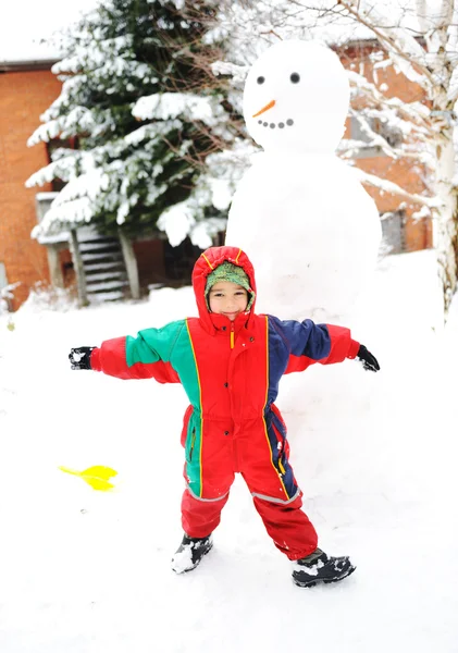 Niños en la nieve con muñeco de nieve —  Fotos de Stock