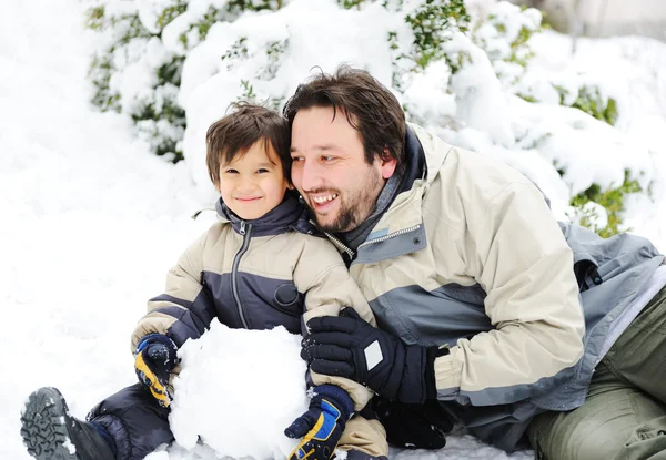 Feliz padre y lindo hijo jugando juntos en la nieve —  Fotos de Stock