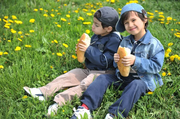Två små vänner äta tillsammans, utomhus — Stockfoto