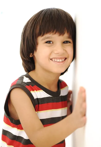 Щасливий хлопчик з довгим волоссям на відкритому повітрі, влітку, стоячи біля стіни — стокове фото