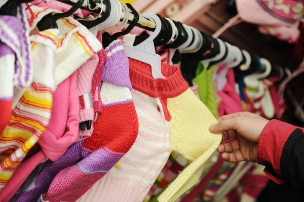 Primo piano di una cliente donna in cerca di vestiti per bambini in una st di moda — Foto Stock