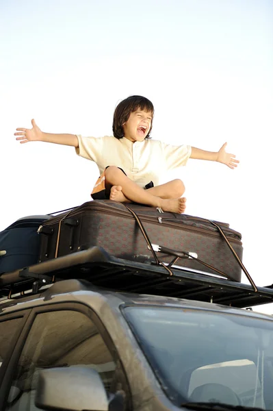 Маленький мальчик путешествует на сумках, на крыше машины — стоковое фото