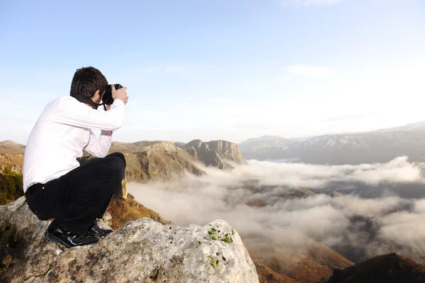 Молодой профессиональный человек с камерой съемки на открытом воздухе, фантастический пейзаж — стоковое фото