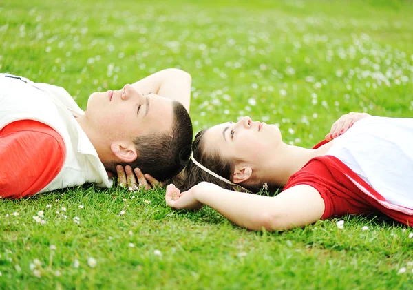 Vista lateral do casal feliz deitado na grama juntos - copyspace — Fotografia de Stock
