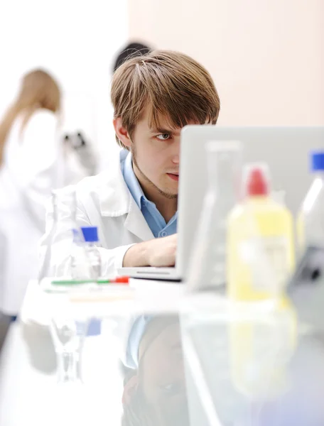 Científico médico joven que trabaja en laboratorio moderno, investigación con tubos y nota — Foto de Stock